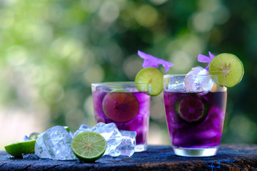 glass of cocktail with ice and lemon on wooden table