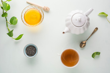 Fototapeta na wymiar Fresh brewed tea, teapot and honey on a light table. White dishes. light background.