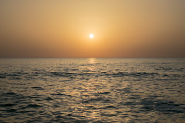 a beautiful sunrise on the seashore. the waves of the sea hit the rocks scattering water. the sun is making its appearance in a new day