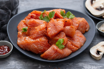 raw meat with spices on dark dish on ceramic background