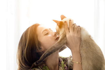 Asian girl holding her cat with window light at home. Copyspace for your text.