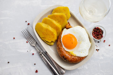 fried smoked portuguese sausage alheira with fried egg and sweet potatoon white dish