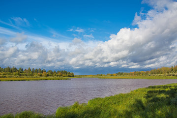 Summer landscape with a river, blue sky and cloud. Before a thunderstorm with rain