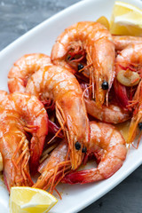 boiled shrimps with lemon on white dish on ceramic  background