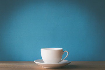 cup of coffee on wooden table with blue background - obrazy, fototapety, plakaty