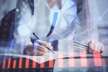 Double exposure of hands making notes with forex chart huds. Stock market concept.