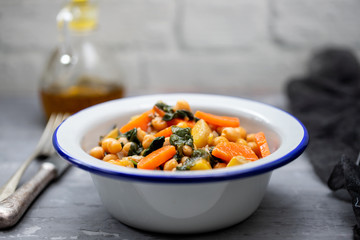 chick-pea with carrot and spinach on white bowl on ceramic background