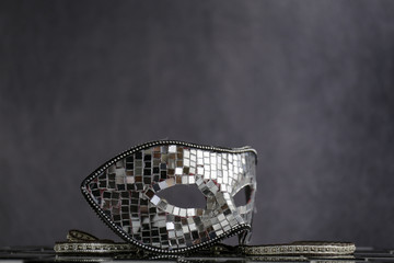 Maschera d'argento sopra la scacchiera bianca e nera con coriandoli  e cristalli