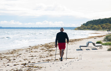 Nordic walking man engaged on the seashore in the morning