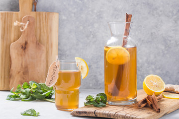 Kombucha or cider fermented drink. Cold tea beverage with beneficial bacteria, cinnamon, lemon on concrete  background side view with copyspace. For healthy nutrition.