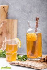 Kombucha or cider fermented drink. Cold tea beverage with beneficial bacteria, cinnamon, lemon on concrete  background side view with copyspace. For healthy nutrition.