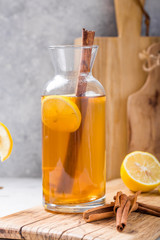 Kombucha or cider fermented drink. Cold tea beverage with beneficial bacteria, cinnamon, lemon on concrete  background side view with copyspace. For healthy nutrition.