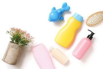 Flat lay photo shampoo bottle, shower gel, liquid soap, hair balm, flowers and toy dolphin on a white background