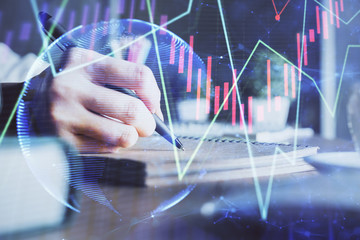 Financial forex charts displayed on woman's hand taking notes background. Concept of research. Double exposure