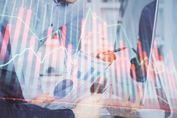 Double exposure of chart with businessman typing on computer in office on background. Concept of hard work.