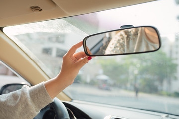 Woman hands adjusting rear view mirror in the car