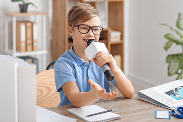 Little journalist with microphone having an interview in office