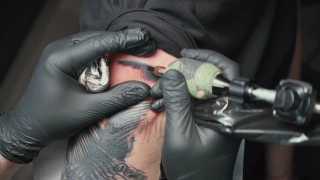 Video of man tattooist getting tattoo of snake in salon