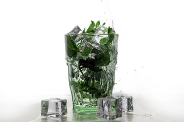 ice and mint fall in a cocktail spray. Rum with mint and ice in a glass.