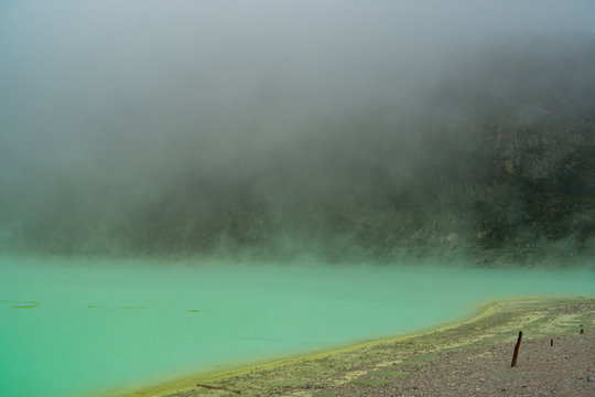 the white crater volcano lake called Kawah Putih on a rainy day. mistic view through the clouds and stunning colours of the water. in Java Indonesia