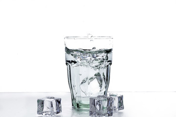 Ice in a glass of water with splashes on a white background.  Clean water in a glass. Cocktail with ice.