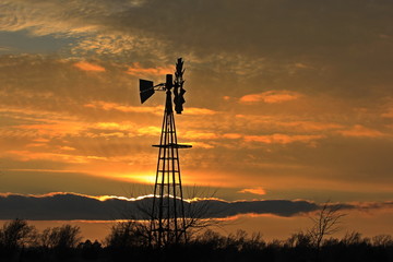 sunset over field with clouds and a Windmill silhouette.