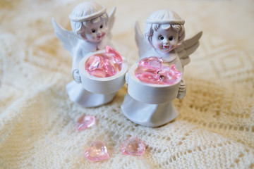 White ceramic figurine of an angel holding a basket with pink hearts, on a light background