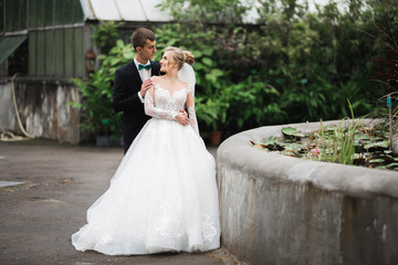 Romantic, fairytale, happy newlywed couple hugging and kissing in a park, trees in background