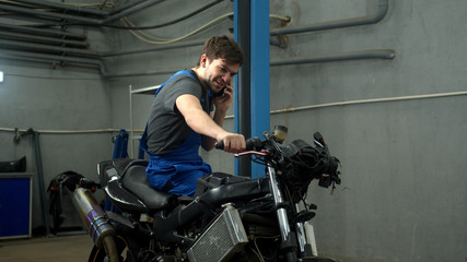 Fototapeta na wymiar Slow motion, technician sits on motorcycle and talks on phone