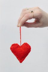 Hand made knitted heart on white wooden background. Valentine's day card with woolen heart and free space. Romantic sign.