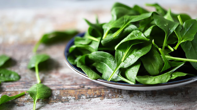 Fresh baby spinach. Washed spinach leaves on a blue plate. Diet concept.