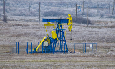 Pump Jack. Oilfield derrick.Oilfield pump for oil production. Vegetation covered with hoar-frost.