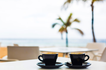 Close up coffee cup on wood table at sunset or sunrise beach