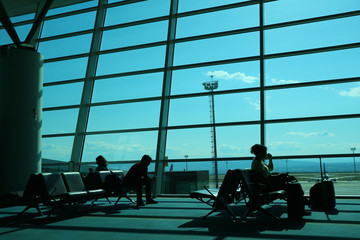 Silhouettes of people in the airport's boarding lounge