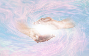 Working with Powerful Divine Energy - male hands emerging from blue pink rotating energy field background with bright white light energy between hands