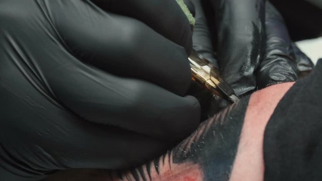 Shooting of tattooist getting black tattoo of snake in salon