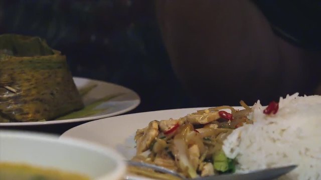 Close Interior Shot of Guest's Hand Using Fork to Scoop up and Eat Rice Dish at Restaurant