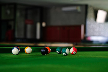 Man's hand and Cue arm playing snooker game or preparing aiming to shoot pool balls on a green billiard table. Colorful snooker balls on green frieze.