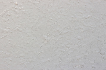 Old white cracked paint on the concrete wall. Texture, pattern, background. The wall cracked with paint