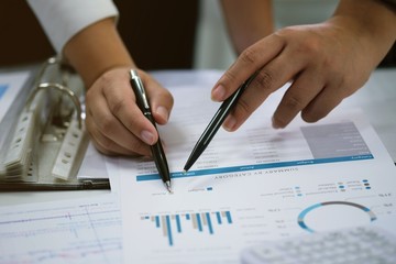 Businessman analyzing investment charts and pressing calculator buttons over documents. Accounting Concept.