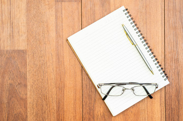 Eyeglasse and notepad on wood deck with copyspace