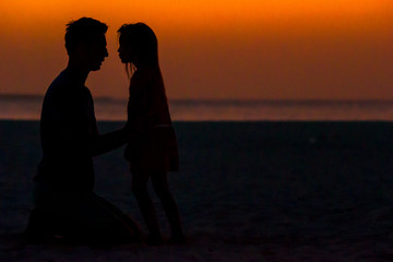 Little girl and dad silhouette in the sunset at the beach
