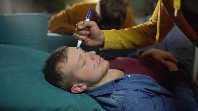 Young guys having fun pranking their sleeping friend, carefree life, party