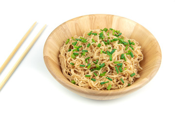 Instant noodles and green onions, cut on a wooden bowl on a white background