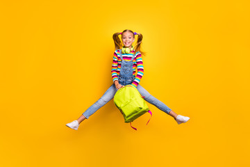 Full size photo cheerful schoolchild jump wear headset striped sweater jeans denim bag rucksack enjoy primary school lesson isolated over bright shine yellow color background