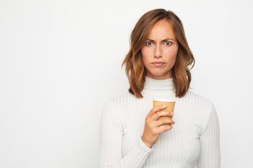 portrait of young woman with cup of coffee looking mad and surprised