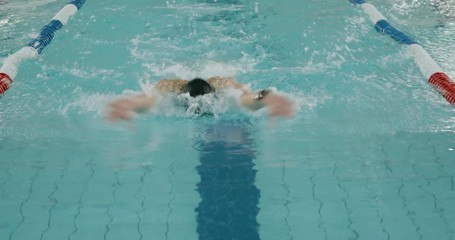 Young professional female swimmer swims in the pool, woman swimming and training in water, butterfly swimming in slow motion.