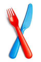 Crossed plastic red fork and blue knife, isolated on white background