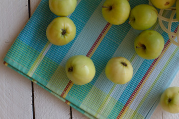 Fresh, ripe Apple harvest. Nature theme with green apples in a white basket on a wooden background. The concept of the nature of the fetus. Top view with space for text