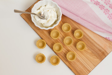 Tartlets with custard or cottage cheese. Empty tartlets or pie on a white table. Food lay flat. The view from the top. The concept of preparing food for the holiday table.